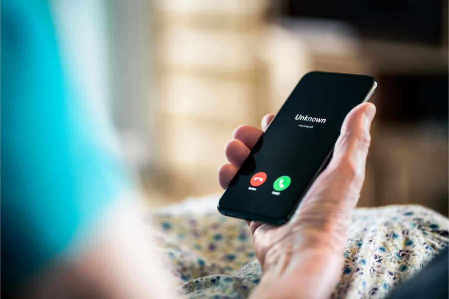 Person hält ein Smartphone mit einem eingehenden Anruf von einer unbekannten Nummer in der Hand.
